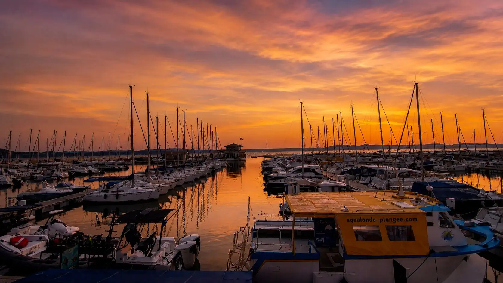 Coucher de soleil incandescent sur le port de La Londe, ciel orange au-dessus des bateaux